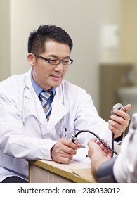 Asian Doctor Measuring Blood Pressure Of A Patient.