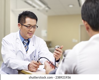 Asian Doctor Measuring Blood Pressure Of A Patient.