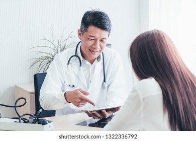 Asian Doctor And Patient Are Discussing Something While Sitting At The Table