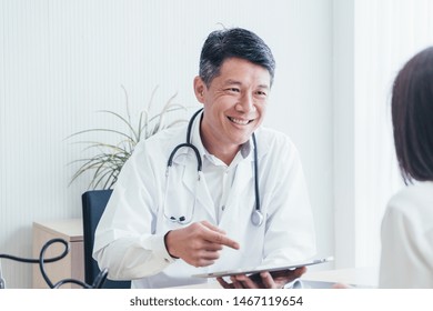 Asian Doctor And Patient Are Discussing Something While Sitting At The Table