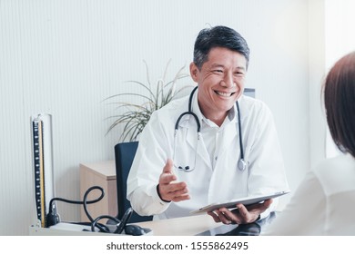 Asian Doctor And Patient Are Discussing Something While Sitting At The Table