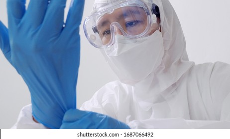 Asian Doctor In Protective Hazmat PPE Suit Wearing Medical Latex Gloves