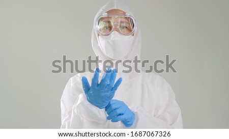Asian doctor in protective hazmat PPE suit wearing medical latex gloves