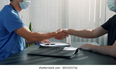 Asian Doctor Shakes Hands With A Patient While Wearing A Mask During The Virus Outbreak.