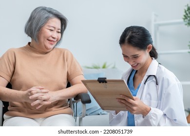 Asian Doctor Showing Health Checkup Report To Grandmother And Giving Advice. Medical Assisted Living Visit Senior Patient At Home. Home Nursing And Healthcare Caregiver Concept