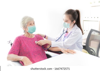 Asian Doctor Talk With Old Female Patient About Disease Symptom, Doctor Use Stethoscope Listening Lung Of Patient,   Elderly Health Check Up , They Wear Surgical Mask On White Background