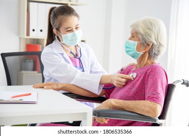 Asian doctor talk with old female patient about disease symptom and use stethoscope listening lung sound of patient, they wearing surgical mask while stay at hospital