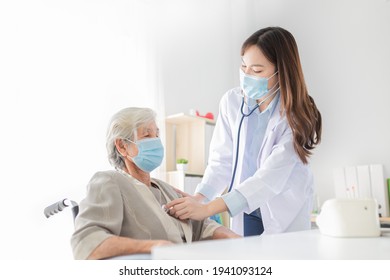 Asian Doctor Talk With Old Female Patient About Disease Symptom, Doctor Use Stethoscope Listening Lung Of Patient, Elderly Health Check Up , They Wear Surgical Mask On White Background, Corona Virus 