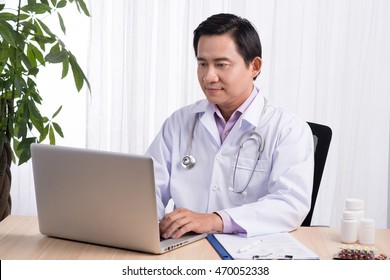 Asian Doctor Typing And Using His Computer In The Office