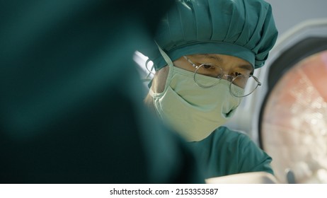 Asian Doctor Uses A Scalpel To The Patient With Surgical Team In Operating Room