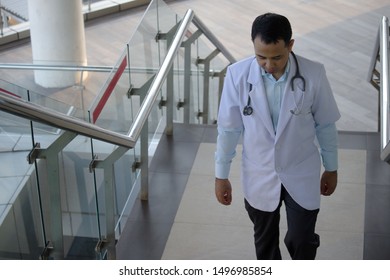 Asian Doctor Walking Up The Stairs In A Modern Building