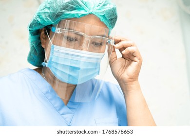 Asian Doctor Wearing Face Shield And PPE Suit To Check Patient Protect Safety Infection Covid-19 Coronavirus Outbreak At Quarantine Nursing Hospital Ward.