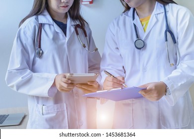 Asian Doctors Holding Clipboard ,iPad Talking And Discussion About Patient At Hospital