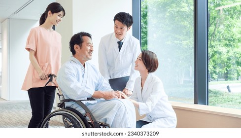 asian doctors talking to a patient in a wheelchair in a hospital - Powered by Shutterstock