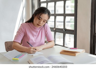 Asian girl student doing exam hand holding pencil writing answer in university classroom education high school or university student taking notes while preparing for exam. - Powered by Shutterstock