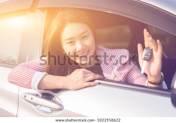 Asian driver woman smiling and showing new car key
while sitting in a car that she taking it from dealer in the auto
show. transport business, sale for consumerism and people
concept,vintage color
