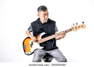 An Asian elder cool man has fashion in gray t-shirt And black vest learn to play bass guitar. Shoot On white background in the studio. Positive active old cool senior healthy retirement concept. - Powered by Shutterstock