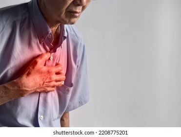 Asian elder man suffering from central chest pain. Chest pain can be caused by heart attack, myocardial infarct or ischemia, myocarditis, pneumonia, oesophagitis, stress, anxiety, etc,.