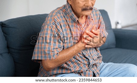 Asian elder man suffering from central chest pain. Chest pain can be caused by heart attack, myocardial infarct or ischemia, myocarditis, pneumonia, oesophagitis, stress, anxiety, etc,.