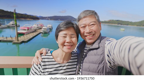 Asian Elderly Couple Have Video Chat By Mobile Phone Happily Outdoor Near Harbor