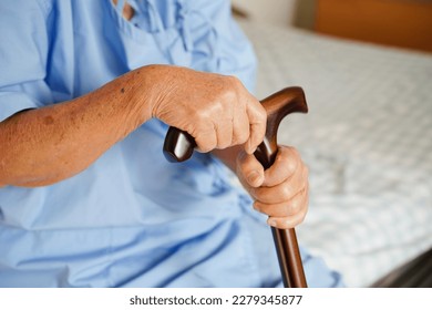 Asian elderly disability woman patient holding walking stick in wrinkled hand at hospital.  - Powered by Shutterstock