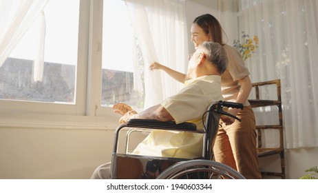 Asian elderly father who sitting on wheelchair show her lovely daughter to look at something through window very happy and smile after he survive from Surgery. Caregivers at Home, Healthcare. - Powered by Shutterstock