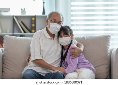 Asian Elderly Grandfather Hug Grandchild And Wearing Face Mask On Sofa At Home Protect Virus Infection