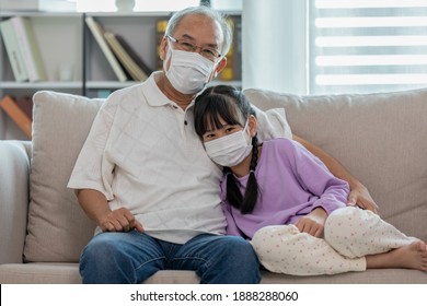 Asian Elderly Grandfather Hug Grandchild And Wearing Face Mask On Sofa At Home Protect Virus Infection