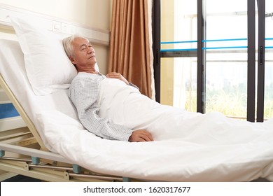 Asian Elderly Male Patient Lying In Bed Sleeping In Hospital Ward Or Assisted Living Facility