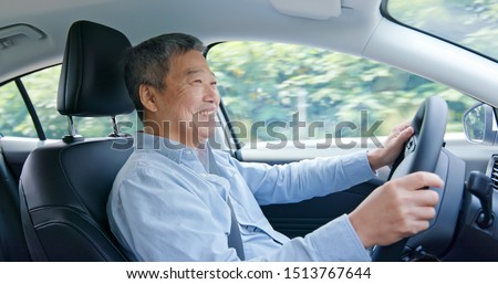 asian elderly man driving happily in the car on highway