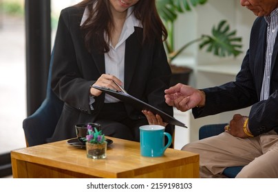 Asian elderly man Interested in investing with young women who offer advice, investment, life insurance, health insurance, stocks - Shutterstock ID 2159198103