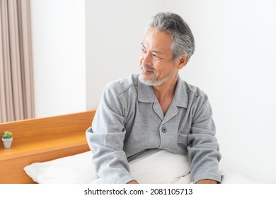 Asian elderly man in night clothes in bed,Smile