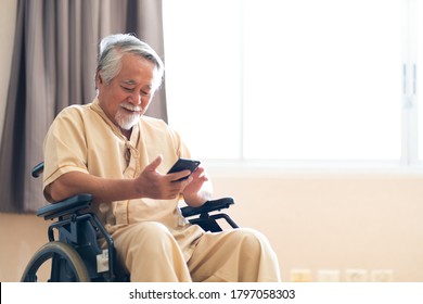 Asian elderly man patient holding mobile phone and conference call meeting to family while sitting on wheelchair at hospital