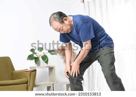 Asian elderly man suffering while holding his knee
