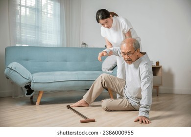 Asian elderly old man with walking stick fall on ground and granddaughter camp to help to support at home in living room, young woman halping her grandfather after falling down on floor, dizziness - Powered by Shutterstock