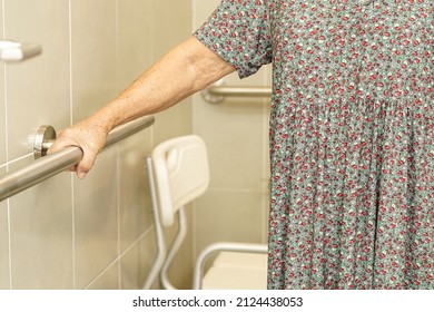 Asian elderly old woman patient use toilet support rail in bathroom, handrail safety grab bar, security in nursing hospital.                       