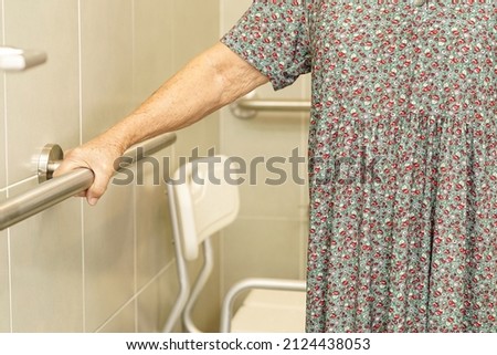 Asian elderly old woman patient use toilet support rail in bathroom, handrail safety grab bar, security in nursing hospital.                       