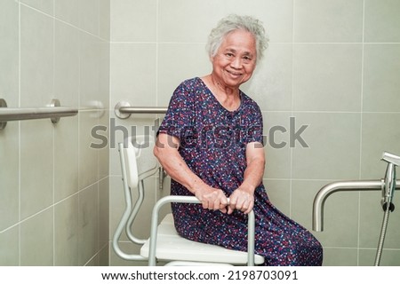 Asian elderly old woman patient use toilet support rail in bathroom, handrail safety grab bar, security in nursing hospital.