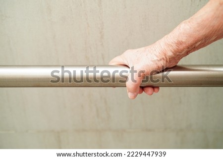 Asian elderly old woman patient use toilet support rail in bathroom, handrail safety grab bar, security in nursing hospital.