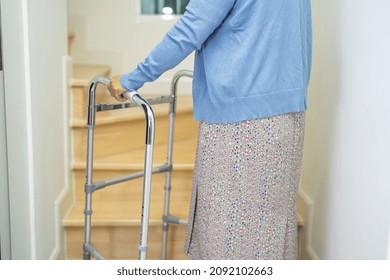 Asian Or Elderly Old Woman Walking With Walker Support Up The Stairs In Home.