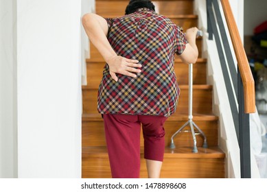 Asian elderly older woman suffering from low-back lumbar pain while walking on stair at home,Lumbar disc herniation