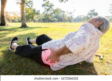 Asian elderly people have an accident because of her walking exercise alone,slipped and fell to the floor,senior woman lying on the ground,touch her painful hips,waist or buttosks after falling down