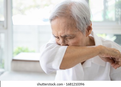 Asian elderly people sneezing,coughing into her sleeve or elbow to prevent spread Covid-19,Corona virus,sick senior woman has flu,fever covering nose,mouth with her arm from dust,air pollution,allergy - Powered by Shutterstock