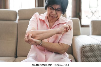 Asian Elderly People Woman Has Elbow Pain Chronic At Home. Older Hand Hold Joint Arm Face With Hurt Emotion.