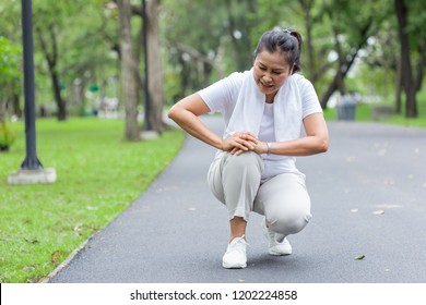 Asian Elderly Or Senior Woman Accident Falling Down On Floor In The Park While Running Exercise Have Pain Knee Ache.