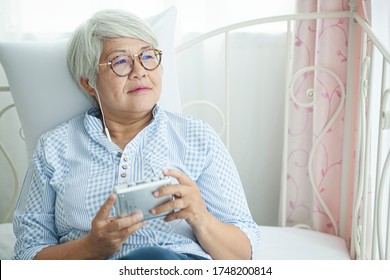 Asian elderly woman listens to home audio during the outbreak of covid-19, concept vit stay home 