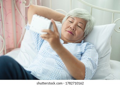Asian elderly woman listens to home audio during the outbreak of covid-19, concept vit stay home
