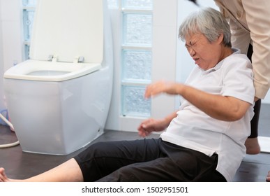 Asian Elderly Woman On Floor In Bathroom After Falling Down Because Slippery Surfaces,caregiver Or Nurse Assisting Care,help,support To Her,senior People Fell To The Floor In Toilet At Nursing Home