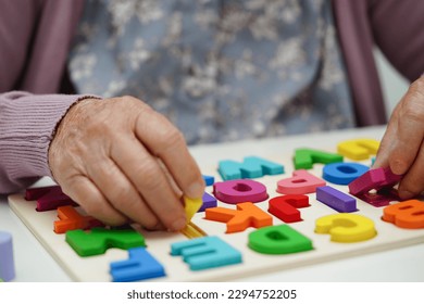 Asian elderly woman playing puzzles game to practice brain training for dementia prevention, Alzheimer disease. - Powered by Shutterstock