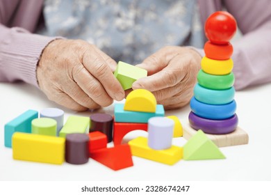 Asian elderly woman playing puzzles game. - Powered by Shutterstock